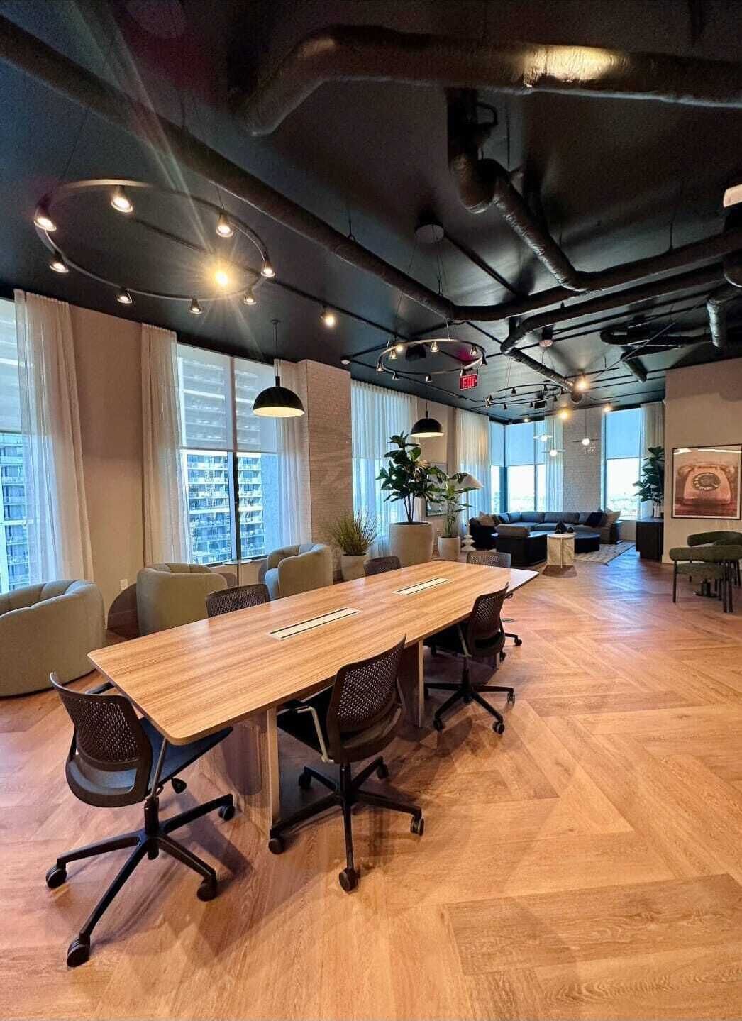 Une salle de conférence avec une longue table en bois, plusieurs chaises et un canapé à l’arrière-plan.