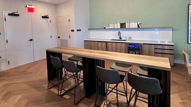 A modern kitchen with a central island, bar stools, and a dining table. - 501 First Residences Miami (Miami)