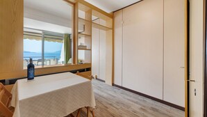 Ein Zimmer mit Tisch, Stühlen, einer Flasche, einem Fenster mit Aussicht und einem Kleiderschrank.