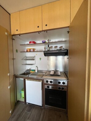 A compact kitchen with a stove, oven, and a small refrigerator.