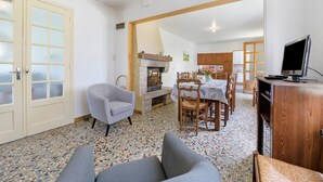 A dining area with a table, chairs, a fireplace, and a television. - Gîte Chez Madeleine: Private Terrace, Garden, and Wi-Fi in Coutances (Coutances)