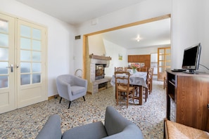 A dining area with a table, chairs, a fireplace, and a television. - Gîte Chez Madeleine: Private Terrace, Garden, and Wi-Fi in Coutances (Coutances)