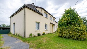 A two-story house with a paved driveway and a well-maintained lawn. - Gîte Chez Madeleine: Private Terrace, Garden, and Wi-Fi in Coutances (Coutances)
