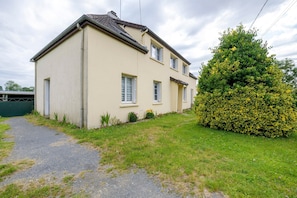 A two-story house with a paved driveway and a well-maintained lawn. - Gîte Chez Madeleine: Private Terrace, Garden, and Wi-Fi in Coutances (Coutances)