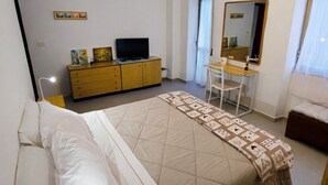 Ein Schlafzimmer mit Bett, Schreibtisch, Stuhl, Fernseher und Kleiderschrank.