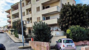Ein mehrstöckiges Wohngebäude mit Balkonen, einem Parkplatz und einer Straße.