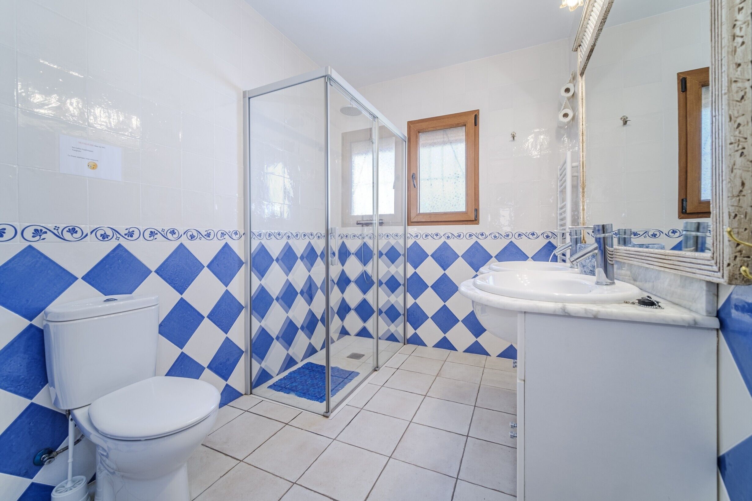 A bathroom with a toilet, shower, and sink, featuring blue and white checkered tiles.