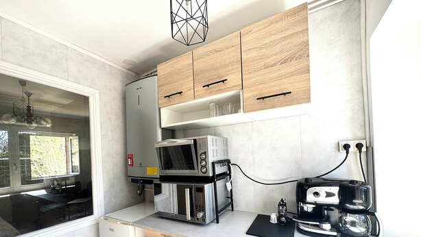 Una cucina compatta con forno a microonde, macchina per il caffè e scaldabagno.