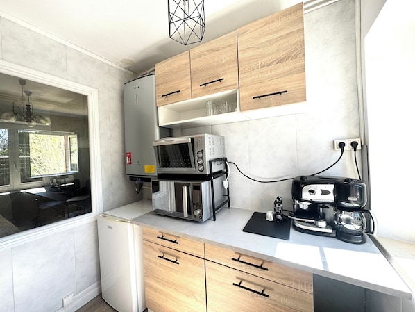 A compact kitchen with a microwave, coffee maker, and a water heater.