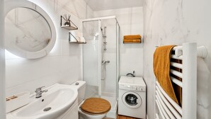 Un bagno funzionale con lavandino, WC, doccia e lavatrice.