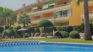 Un hôtel doté d’une piscine, de palmiers et d’une pelouse bien entretenue.