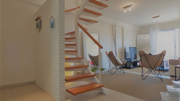 Un intérieur moderne avec un escalier en colimaçon, un coin repas avec des chaises et un téléviseur.