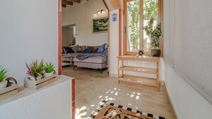 A cozy living room with a sofa, a wooden table, and a window with a view of greenery. - Holiday Home 'Jávea - Just Steps from the Sea' with Private Terrace, Wi-Fi & AC (Jávea)