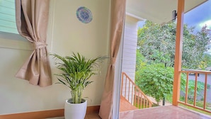 Un balcon agrémenté d’un pot de fleurs, d’un tapis à motifs et offrant une vue sur la verdure.