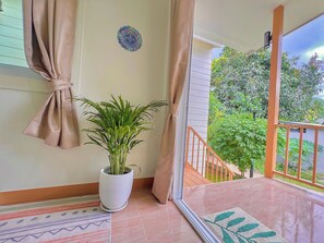 A balcony with a potted plant, a patterned rug, and a view of greenery. - Stylish Tropical Cottage in Chaloklum Heart, 3 Min Walk to Beach (Tambon Ko Pha-ngan)