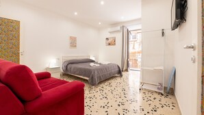 Une chambre à coucher avec un lit, un fauteuil rouge, une télévision et un espace douche.