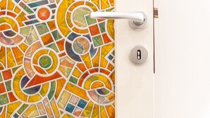 Une porte ornée d’une mosaïque aux couleurs vives et dotée d’une poignée blanche.