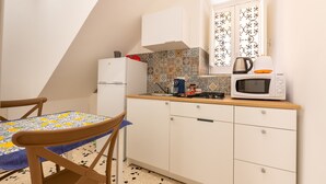 Une petite cuisine équipée d’un réfrigérateur, d’un four à micro-ondes et d’une machine à café posée sur le plan de travail.