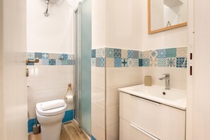 A bathroom with a toilet, sink, shower, and tiled walls. - Holiday House Annunziata 2 Apartment with Balcony, Wi-Fi and Air Conditioning (Termini Imerese)