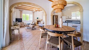 A spacious living area with a round wooden table, wicker chairs, and a television. - Holiday Home 'Del Sol' with Mountain View, Wi-Fi, and Air Conditioning (Xàbia)