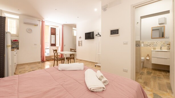 A hotel room with a bed, a desk, a chair, a television, and a bathroom. - Holiday House Annunziata 1 Apartment with Wi-Fi and Air Conditioning (Termini Imerese)