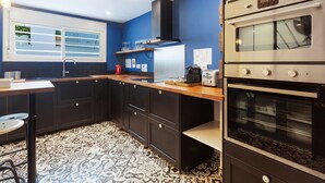 Una cocina moderna con armarios oscuros, suelo estampado y electrodomésticos de acero inoxidable.