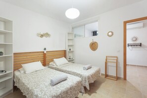 Une chambre d’hôtel avec deux lits, une tête de lit en bois, une petite étagère et un miroir.