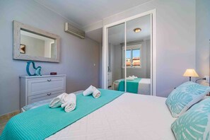 Una habitación de hotel con cama, espejo, cómoda, ventana y lámpara.