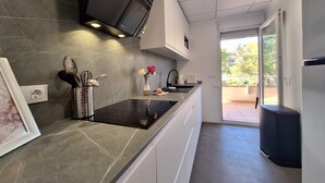 Une cuisine moderne équipée d’une cuisinière intégrée, d’un téléviseur à écran plat et offrant une vue sur l’extérieur.