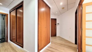 Un couloir avec des portes en bois, un espace douche et un sol de couleur claire.