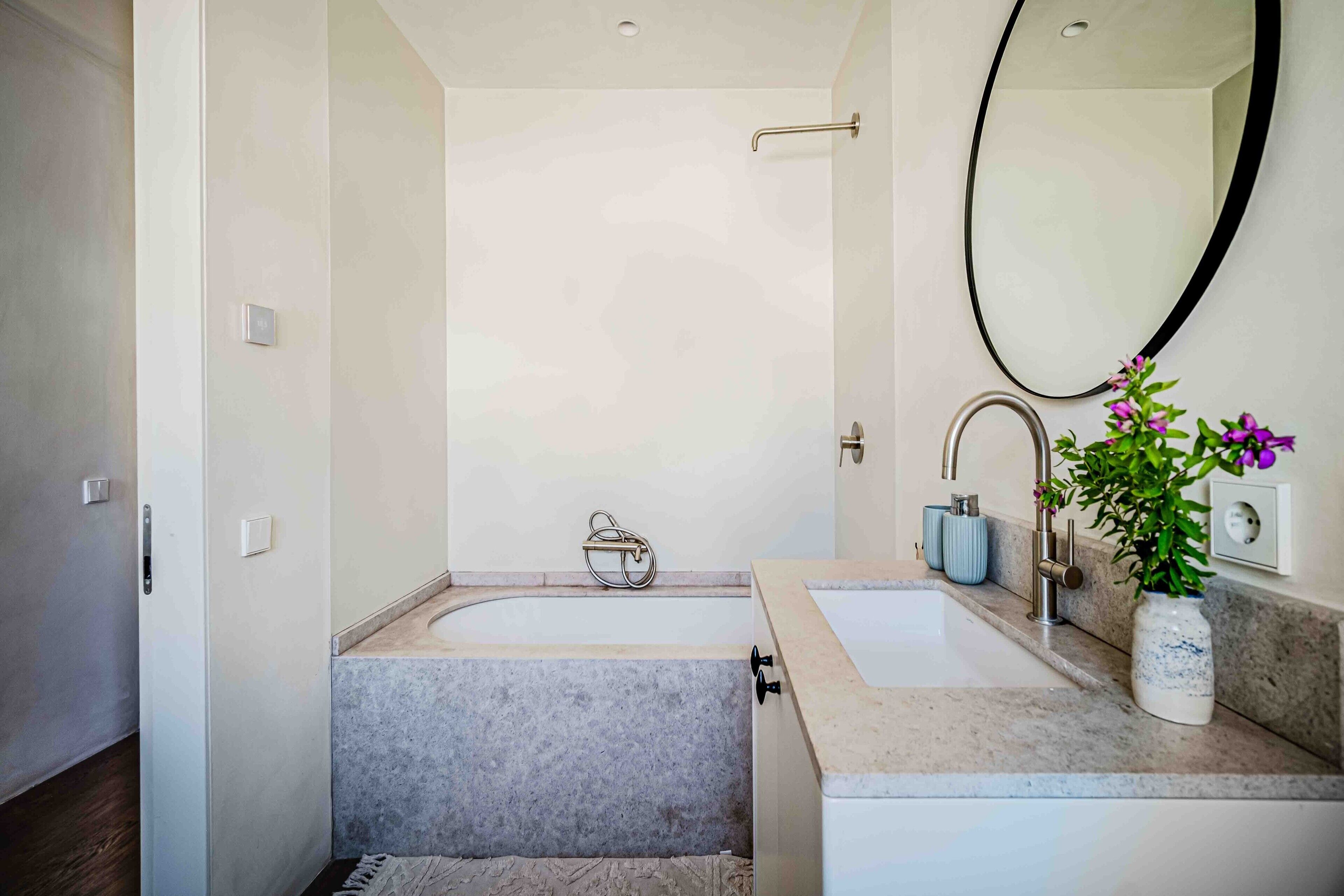 Une salle de bain moderne avec une baignoire, deux lavabos, un miroir et une plante en pot.