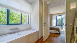 Un baño moderno con bañera, ducha y un amplio ventanal.