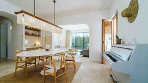 Un interior moderno con comedor, piano y ventanas amplias.