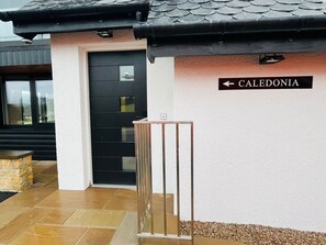 Une entrée d’immeuble avec une porte noire, un portail en métal et une enseigne indiquant « CALEDONIE ».
