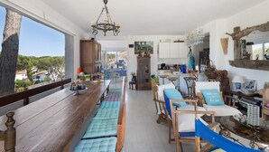 A spacious kitchen with a long wooden table, a chandelier, and a view of the outside. - Villa with Pool 800 Meters from Playa de Pals (Pals)