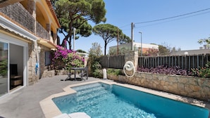 A swimming pool with a stone wall, a patio with a table and chairs, and a stone building with a balcony. - Ground Floor Apartment with Private Pool (Sa Riera)