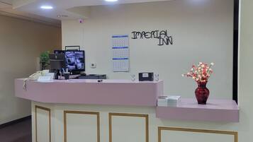 A reception desk with a calendar, a security camera, a phone, and a vase with flowers.