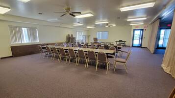 A conference room with a long table, chairs, ceiling fans, and exit signs.