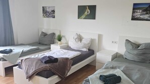 Un dormitorio moderno con dos camas, una mesita de noche con lámpara y decoración en la pared.