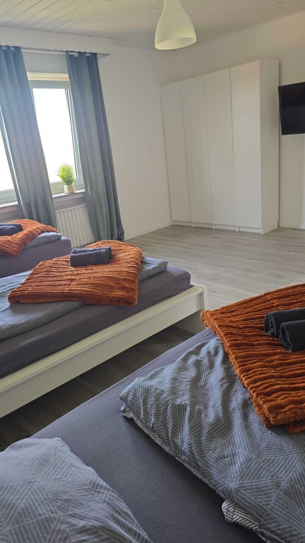Una habitación con dos camas, televisión y ventana con cortinas.
