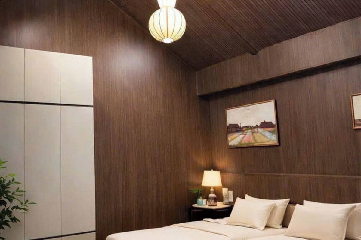 A bedroom with a wooden ceiling, two beds, a nightstand, a lamp, and a painting on the wall.