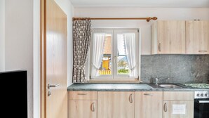 Eine Küche mit Holzausstattung, einer Spüle aus Edelstahl und einem Fenster mit Vorhängen.
