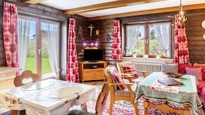 A cozy cabin interior with a dining table, a sofa, a television, and a fireplace. - Apartment 'Parterre' with Mountain View, Private Terrace and Wi-Fi (Wallgau)