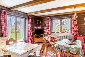 A cozy cabin interior with a dining table, a sofa, a television, and a fireplace. - Apartment 'Parterre' with Mountain View, Private Terrace and Wi-Fi (Wallgau)