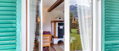 Ein Zimmer mit Bett, Sessel, kleinem Tisch und Fenster mit Bergblick.