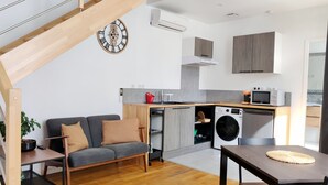Una cocina moderna con lavadora integrada, una mesa de comedor y un sofá.