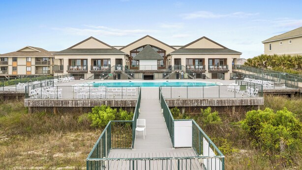 Un resort con piscina central, varios balcones y una terraza de madera que da a la piscina.