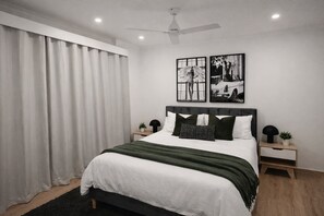 Una camera da letto moderna con un letto, tende, una ventola a soffitto, comodini e decorazioni alle pareti.