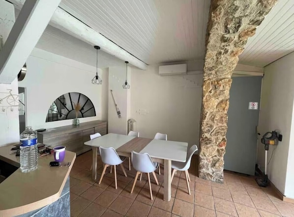 A dining area with a stone column, white table, and chairs. - Vacation home 10 persons (Port-la-Nouvelle)