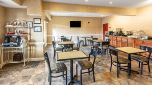 A restaurant with tables and chairs, a coffee station, and a television on the wall. - Spark by Hilton Douglasville Atlanta West (Douglasville)